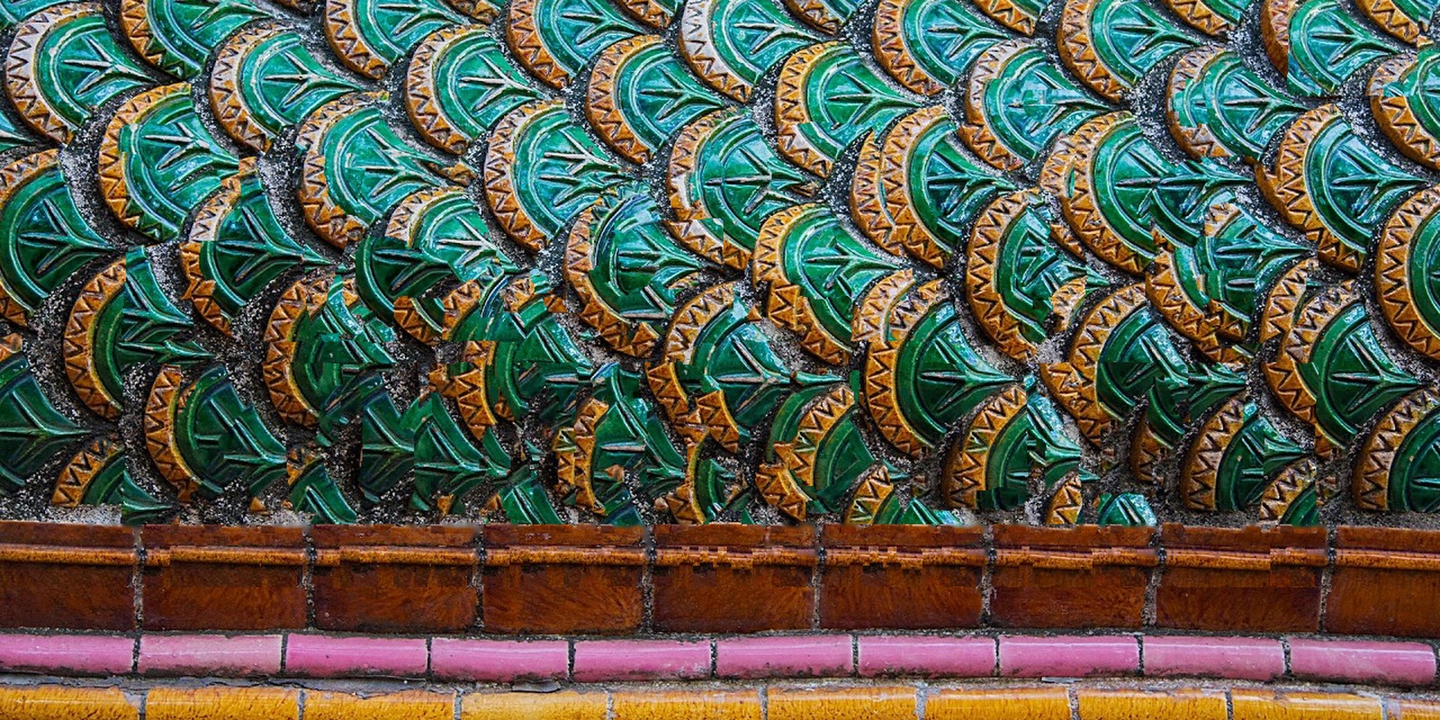 Green and gold glazed ceramic serpent scales on a temple wall above rows of brown, pink and yellow tiles, Living with Reality Ep. 54 Nāgas and Kundalini